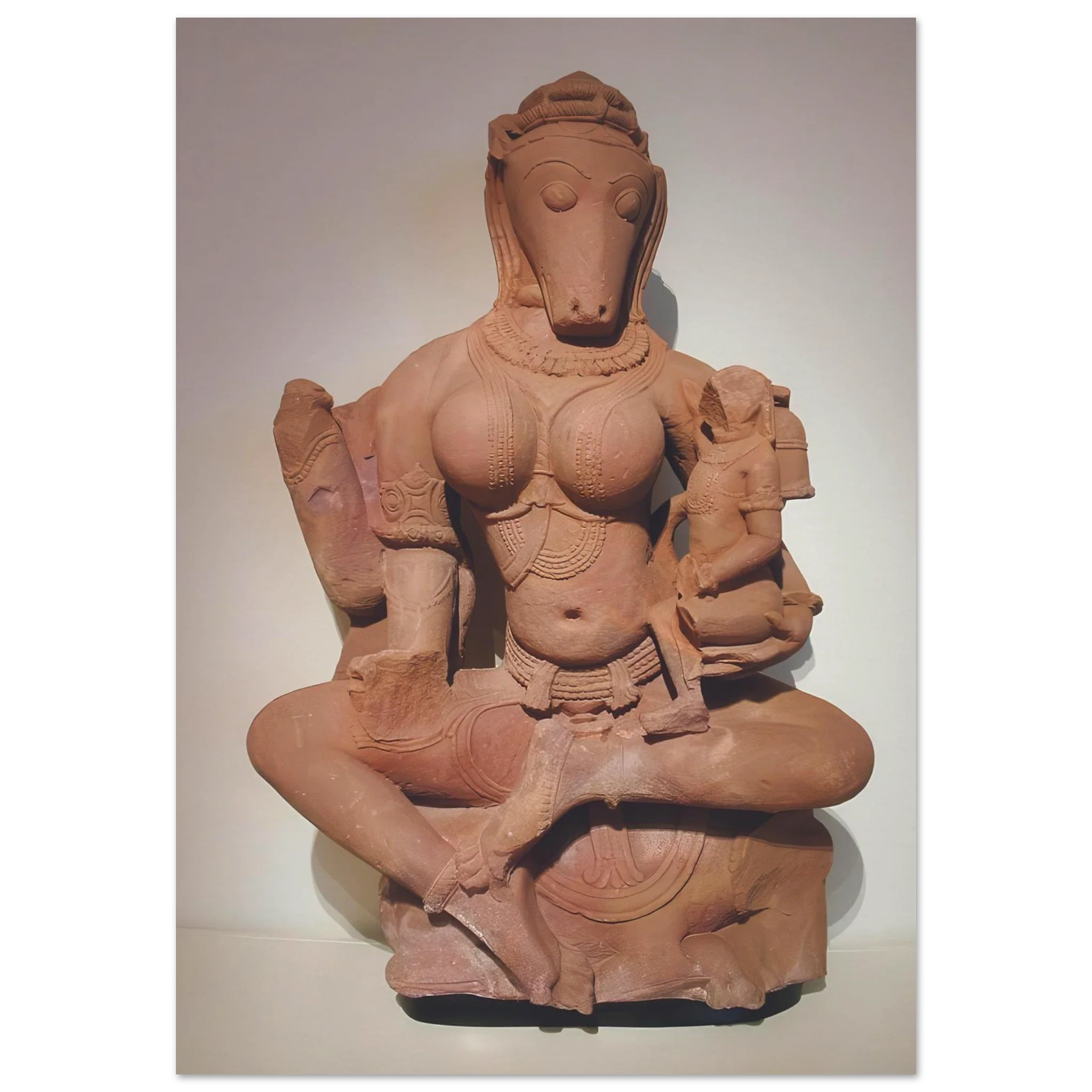 Sandstone sculpture of horse-headed Yogini Hayagriva seated cross-legged and holding a child