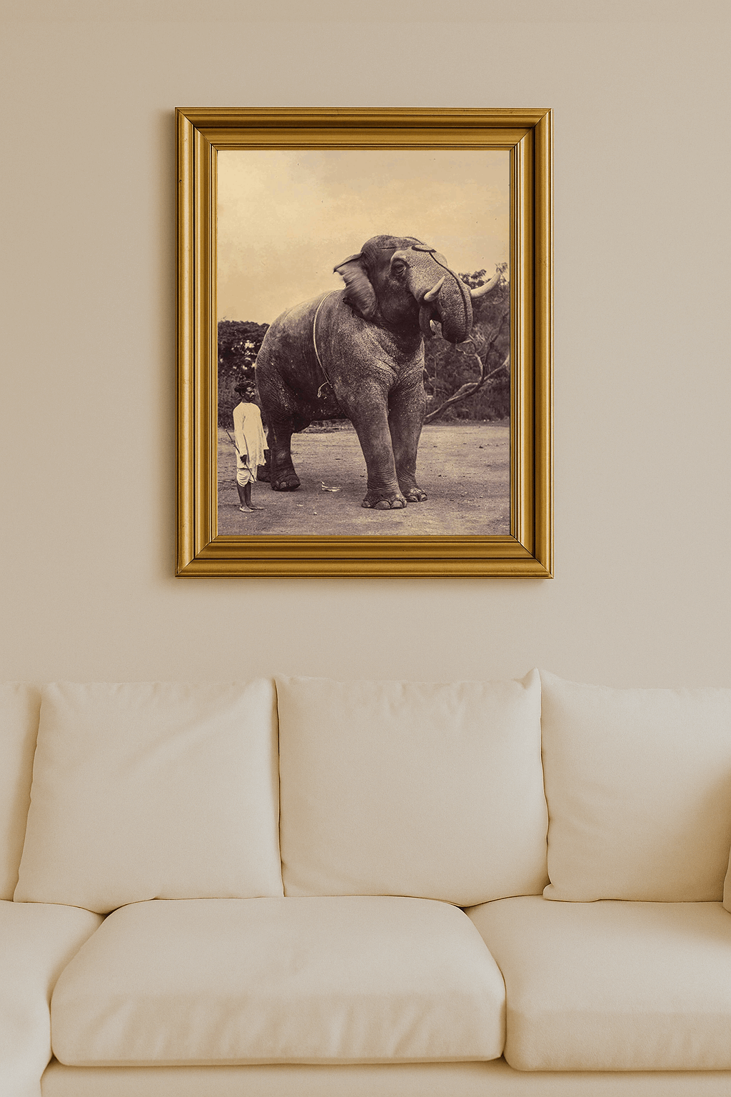 Sepia-toned photograph of a large elephant beside a man holding a stick