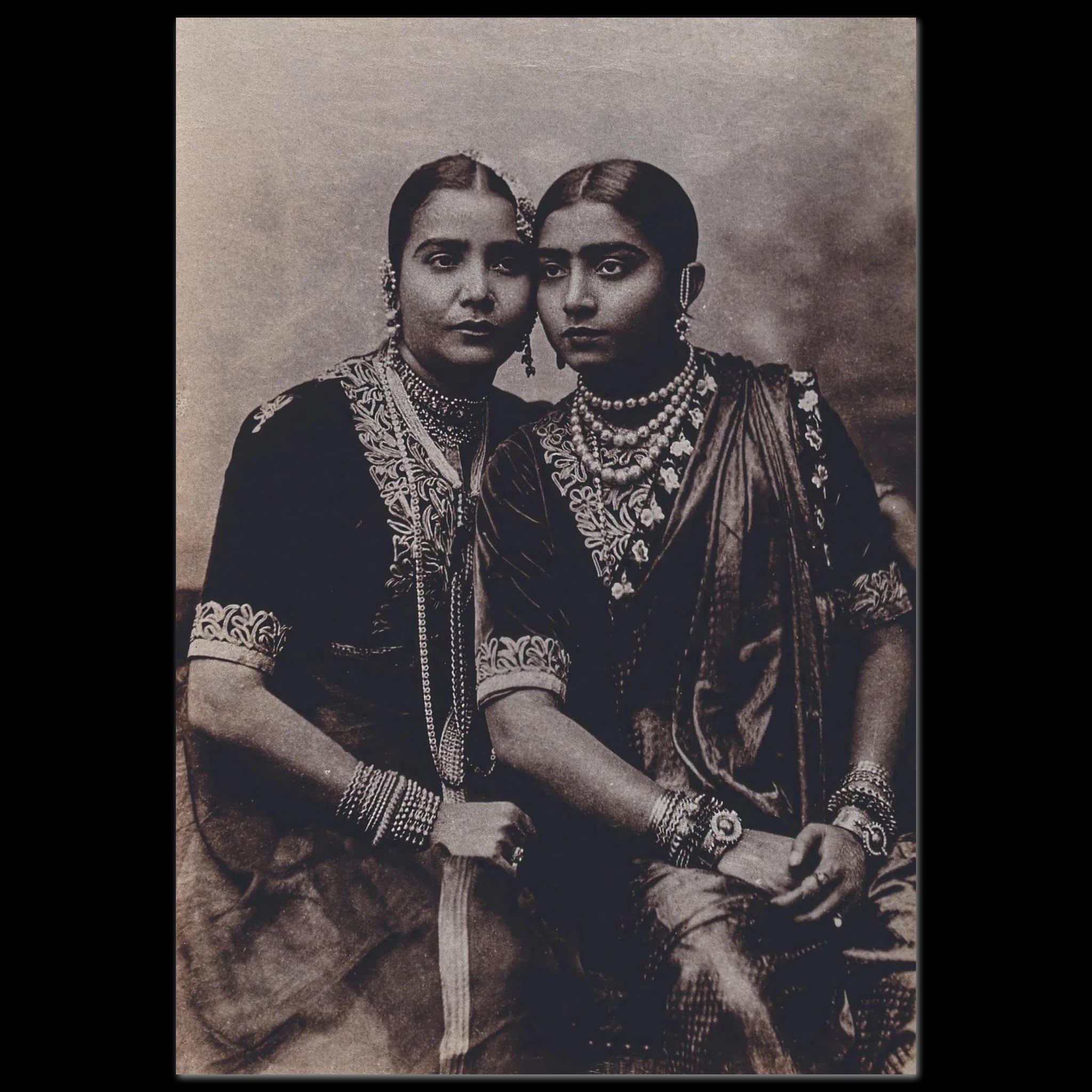 Sepia-toned photograph of two Nautch dancers in traditional embroidered garments and ornate jewelry, seated closely